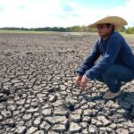 Homem agachado sobre terra seca