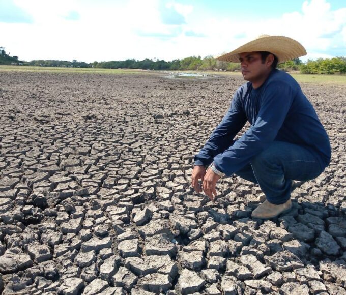 Homem agachado sobre terra seca