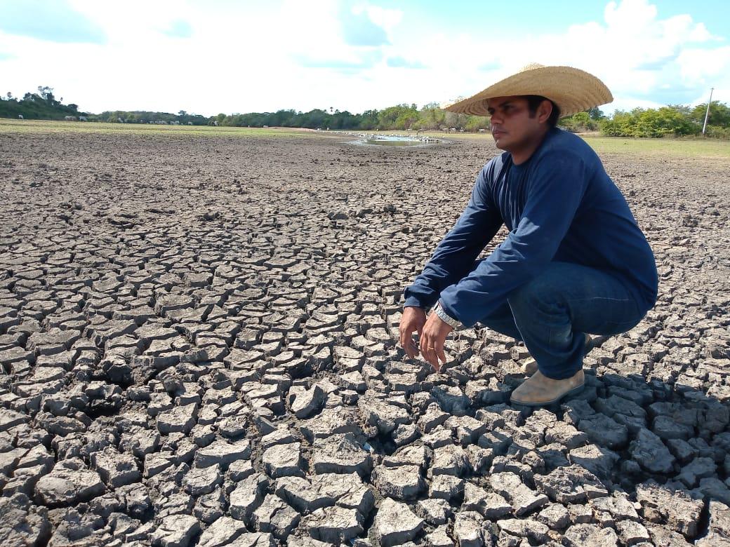 Homem agachado sobre terra seca