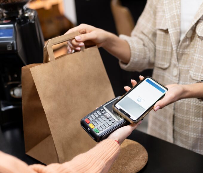 Imagem mostra pessoa usando o smartphone para pagar comprar; comércio, varejo